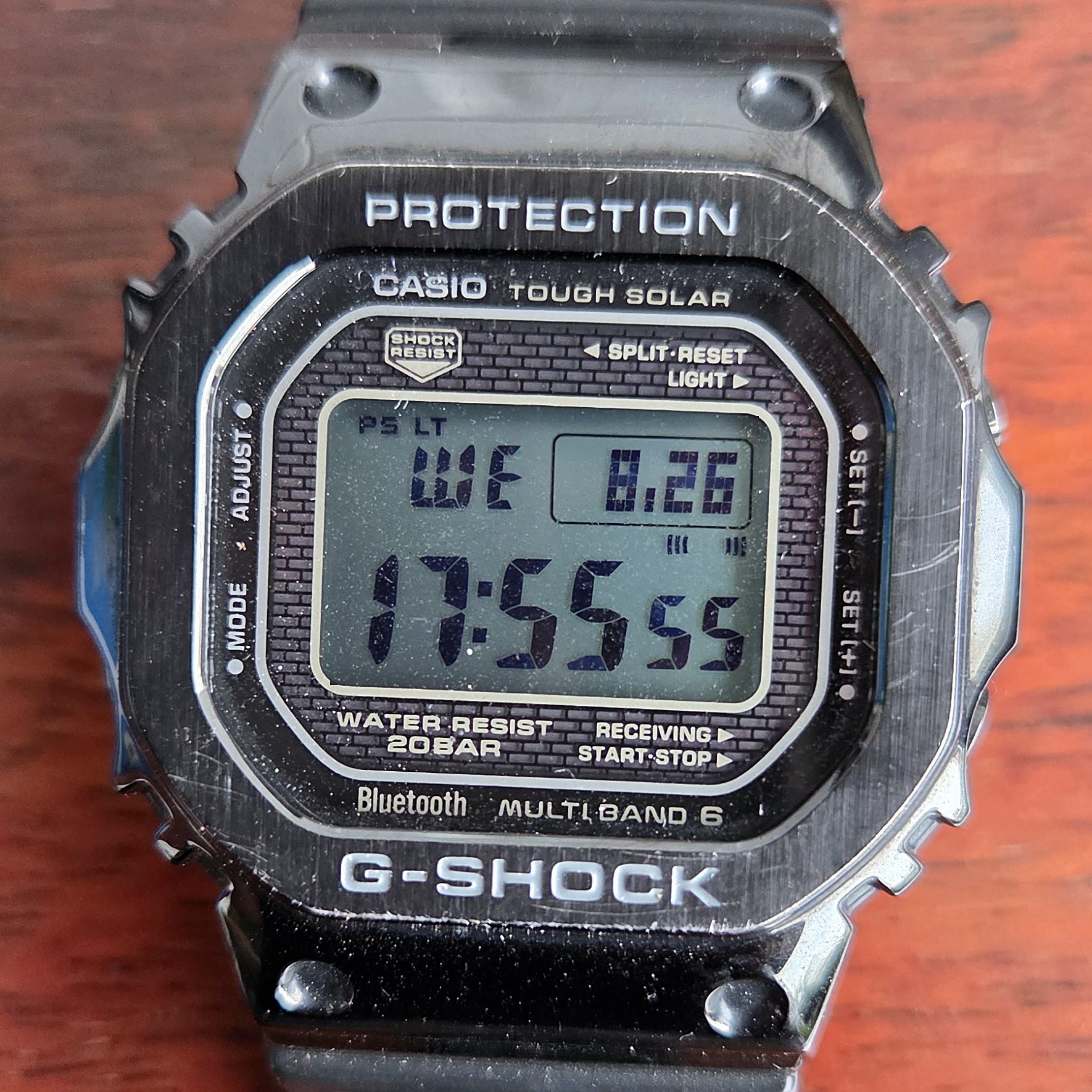 A full-metal Casio G-Shock square with a black finish, its negative LCD showing the time.