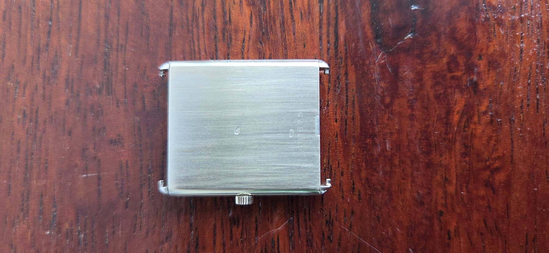 The plain brushed rectangular case back, with no engraving on the outside.
