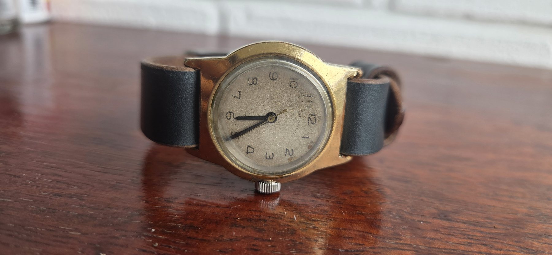 A three-quarter view of the watch on its black leather strap.